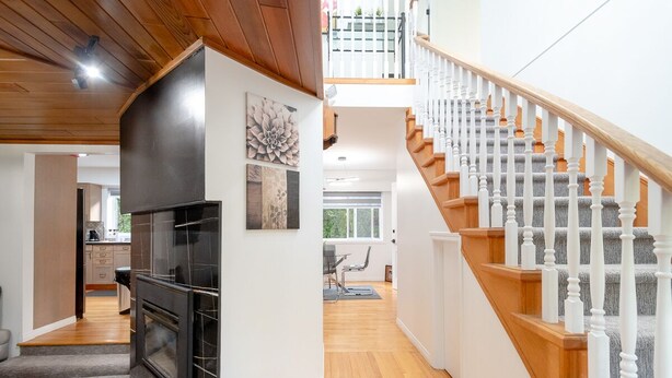 Una cocina moderna con estufa negra, suelo de madera y una escalera con balaustres blancos.