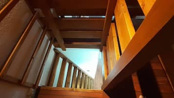 A wooden staircase with a view of the sky through the gaps in the balusters.
