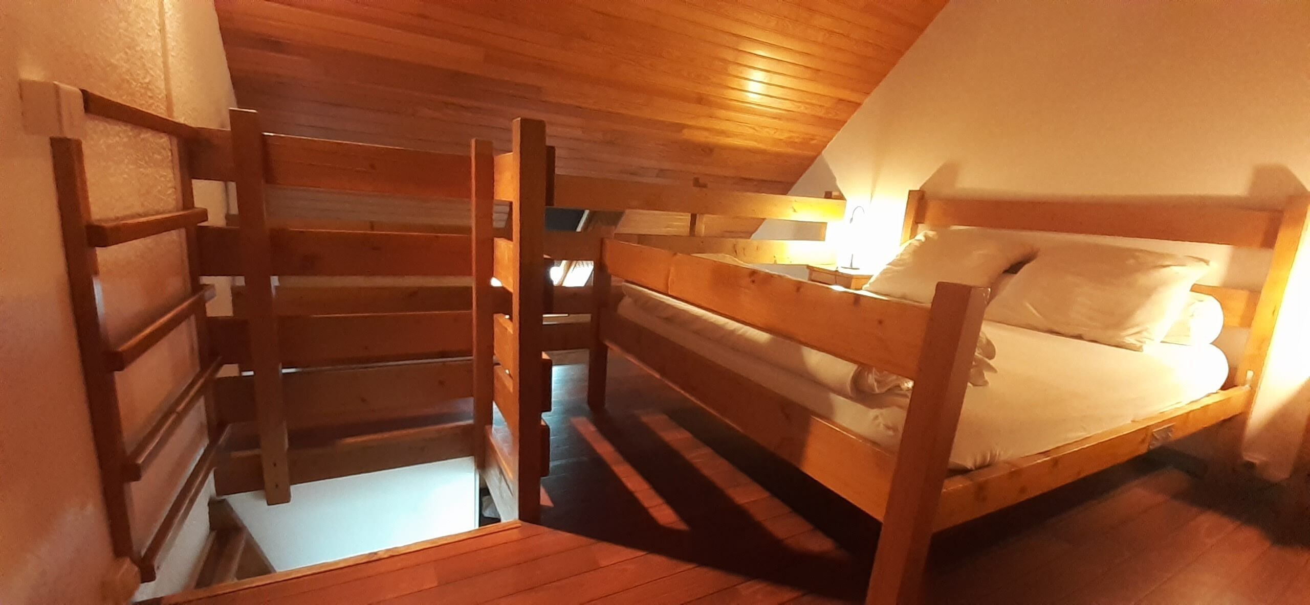 A wooden bunk bed room with a ladder leading to an upper bunk.