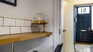 A hallway with a wooden shelf, a glass dome display case, and a door with a number sign. - The Book Club, York. (York)