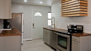 A modern kitchen with stainless steel appliances, a wooden countertop, and a built-in oven.