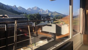 Un balcon avec vue sur les montagnes et une maison en arrière-plan.