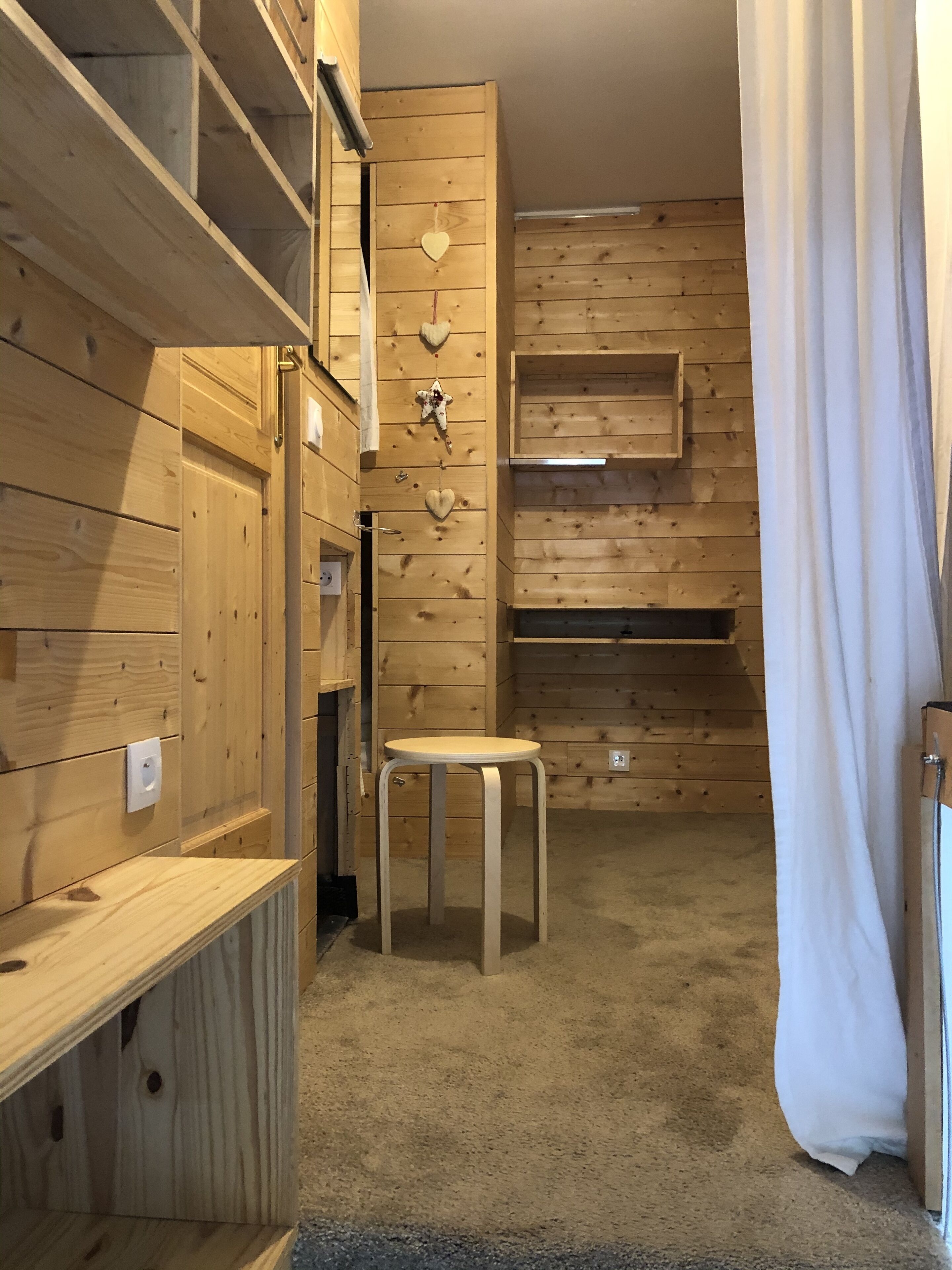 A wooden interior with built-in shelves, a small round table, and a curtain.