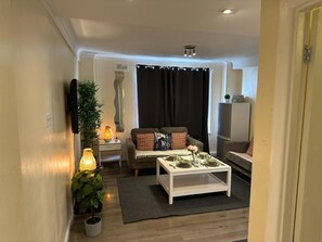 Een knusse woonkamer met een bank, een bijzettafeltje en een eettafel gedekt voor twee personen.
