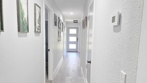 Ein Korridor mit weißen Wänden, Holzboden und gerahmten Kunstwerken an den Wänden.