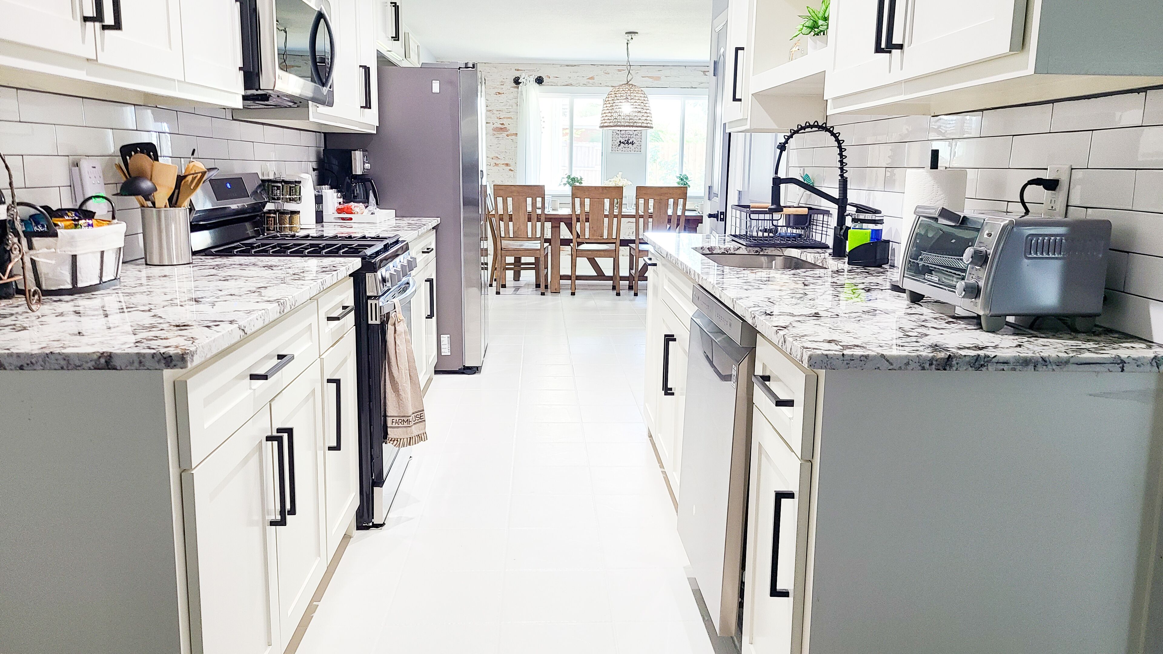Una cucina moderna con mobili bianchi, un'isola centrale e un'area pranzo con sedie in legno.