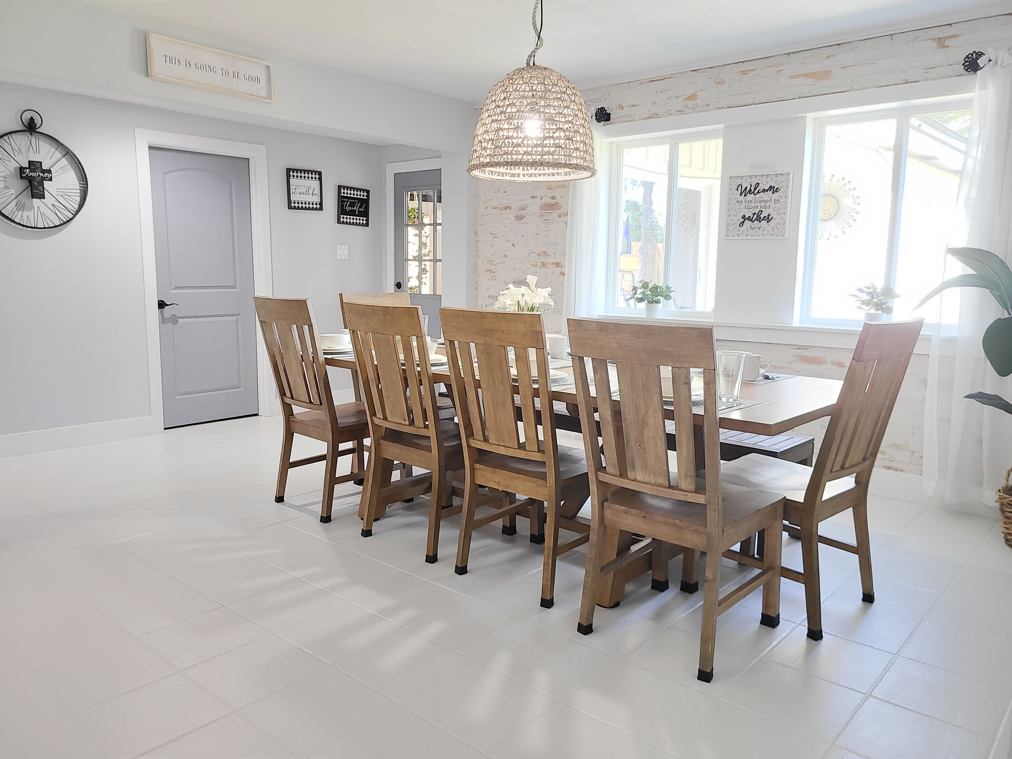 Comedor con mesa y sillas de madera, lámpara colgante y pared con citas inspiradoras.