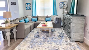 Ein Wohnzimmer mit Ecksofa, Couchtisch, Fernseher und Schrank.