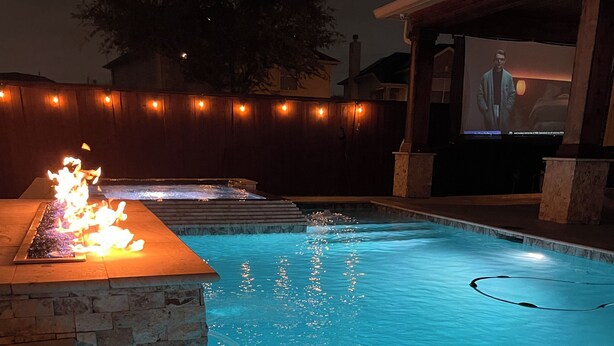 Piscina com lareira e tela exibindo uma pessoa.