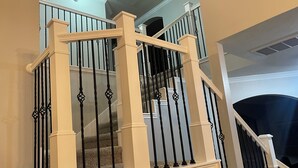 Uma escadaria com balaústres brancos e corrimãos pretos, que leva a um andar superior.