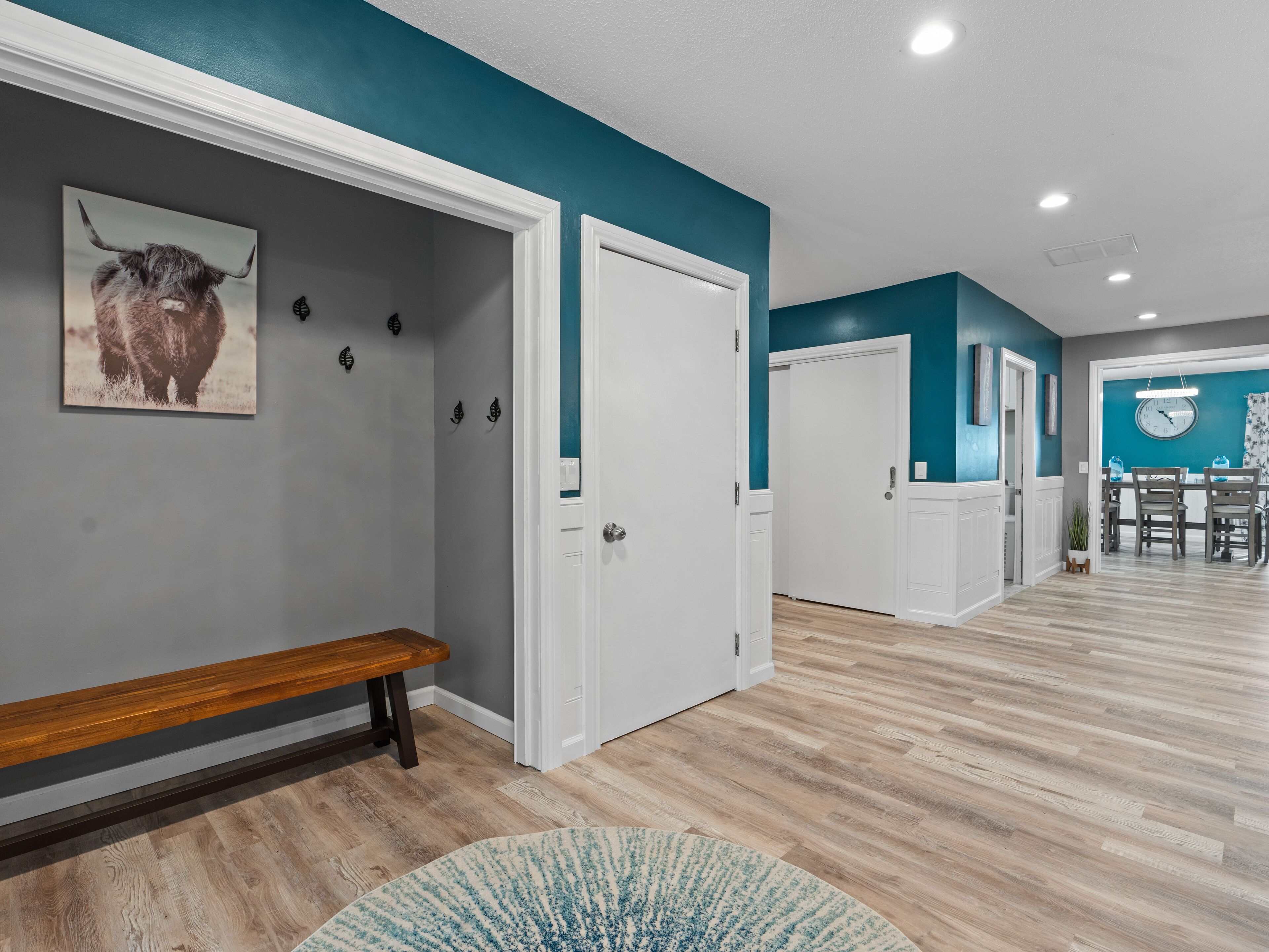 A hallway with a bench, a door, and a wall-mounted clock.