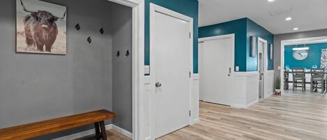 A hallway with a bench, a door, and a wall-mounted clock.