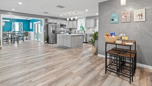 A modern kitchen with grey cabinets, stainless steel appliances, and a wooden dining area.
