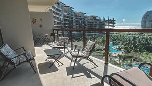 Ein Balkon mit Blick auf ein Resort, inklusive Pool und Palmen.