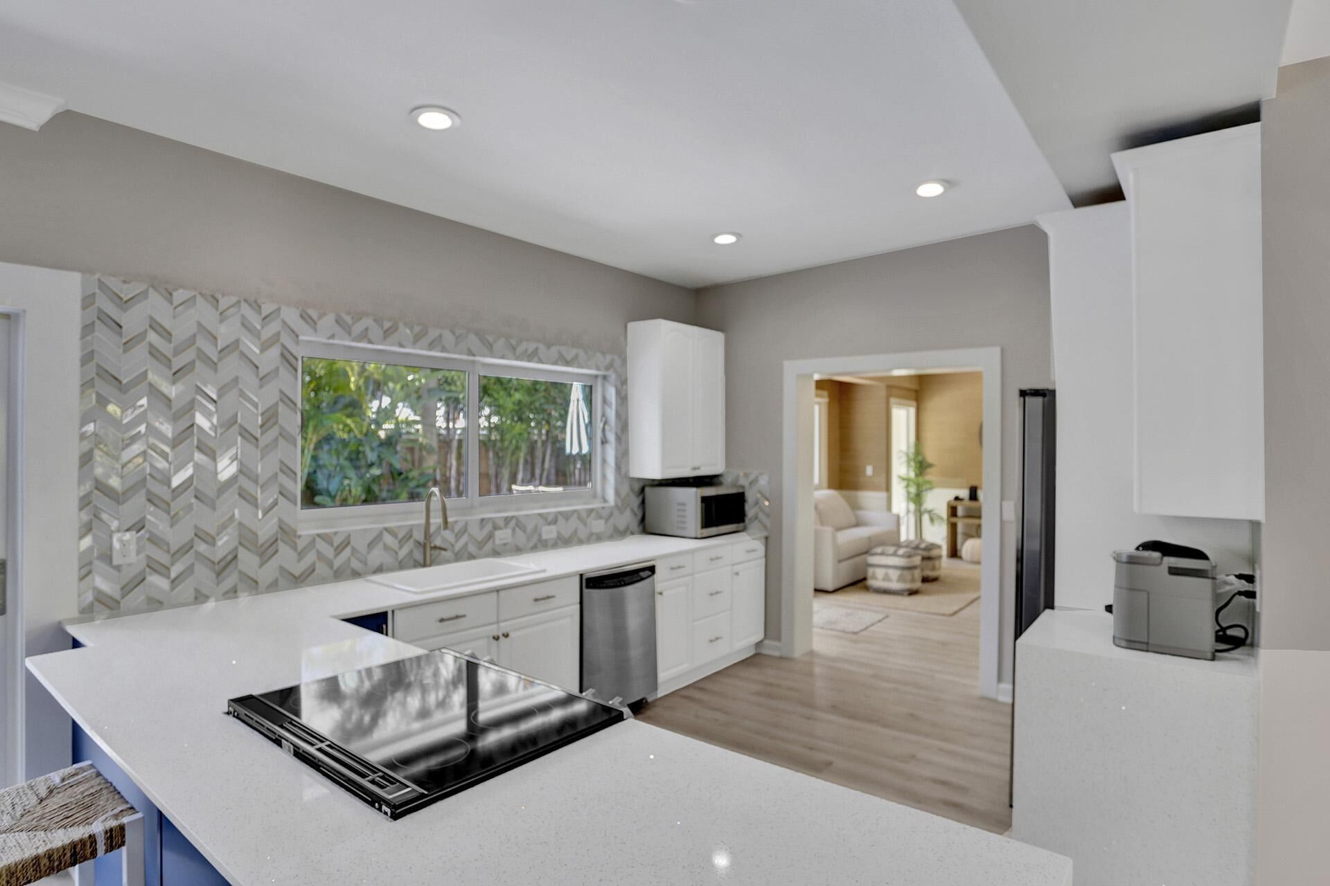 A modern kitchen with a large island, built-in appliances, and a herringbone-patterned backsplash.