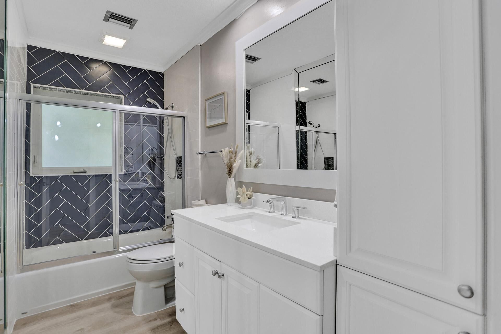 Un baño moderno con cabina de ducha de vidrio, un lavabo blanco y un espejo grande.