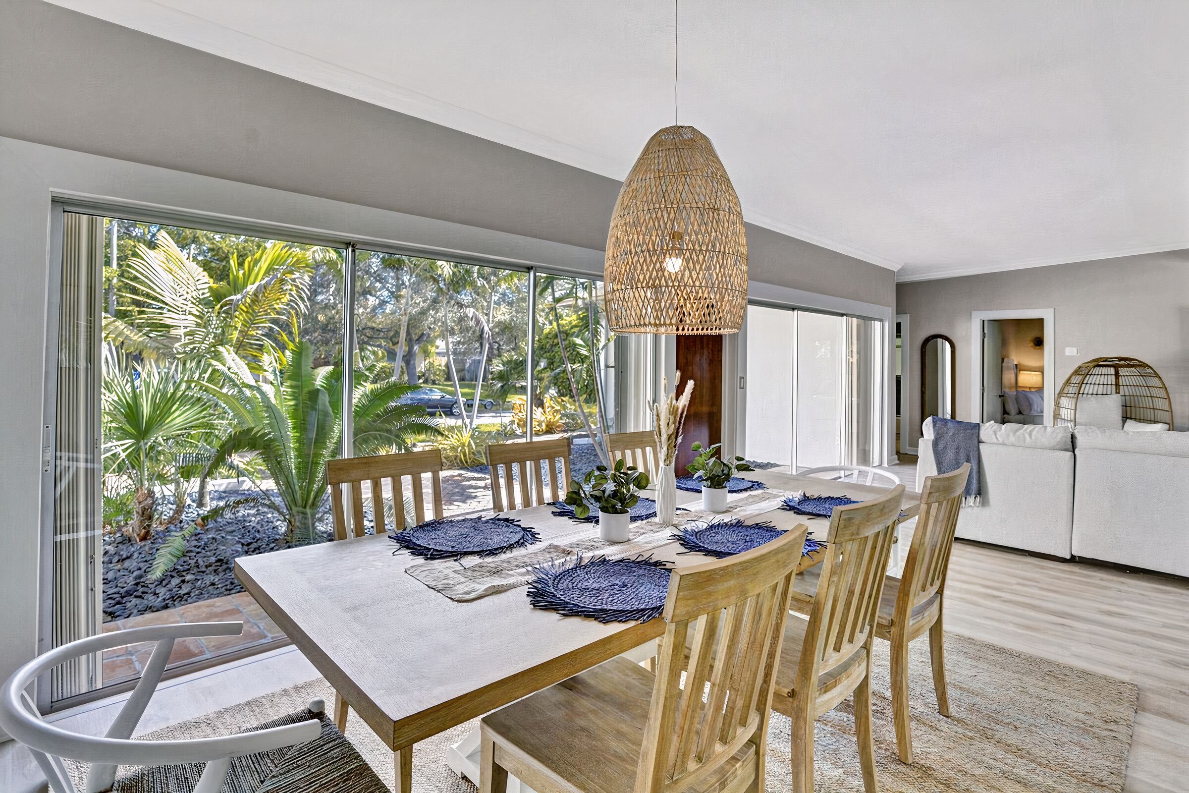 A modern dining area with a large table, wooden chairs, and a hanging light fixture.