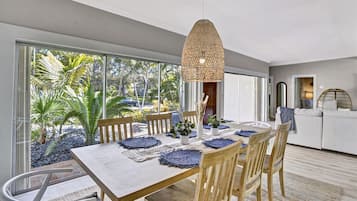 A modern dining area with a large table, wooden chairs, and a hanging light fixture.