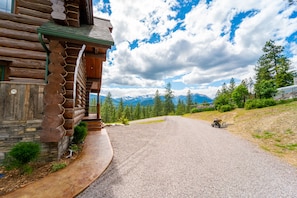 Une cabane en rondins avec des fondations en pierre, une allée en gravier et une vue sur la montagne.