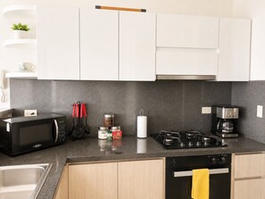 A modern kitchen with a microwave, stove, coffee maker, and cabinets. - U-GO Edificio Murano Elite, Bocagrande (Cartagena)
