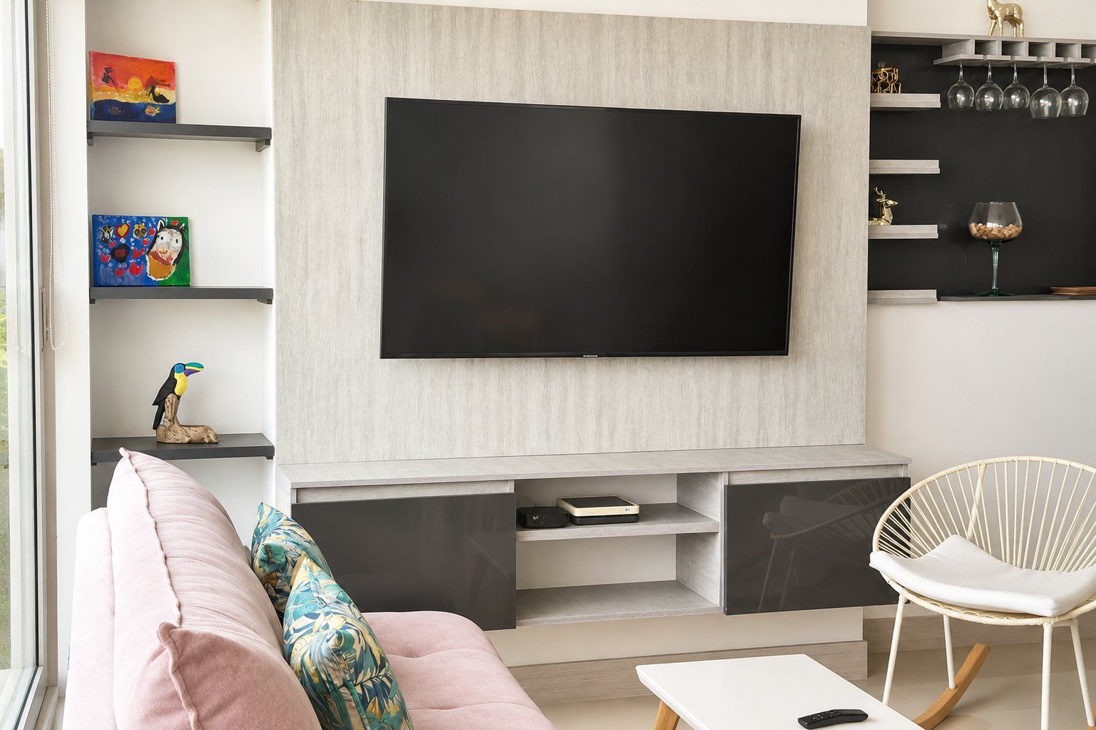 Ett modernt vardagsrum med en platt-TV, en soffa, en fåtölj och ett soffbord.