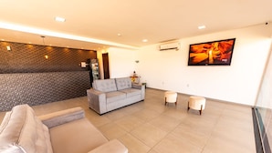 A modern living area with a grey sofa, two round ottomans, and a patterned wall. - BARRA DE MARAGOGI (Maragogi)