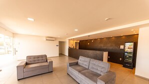 A spacious lobby with two grey sofas, a reception desk, a patterned wall, and a vending machine. - BARRA DE MARAGOGI (Maragogi)