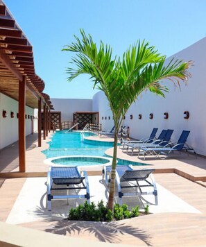 A pool area with multiple sun loungers and a palm tree. - BARRA DE MARAGOGI (Maragogi)