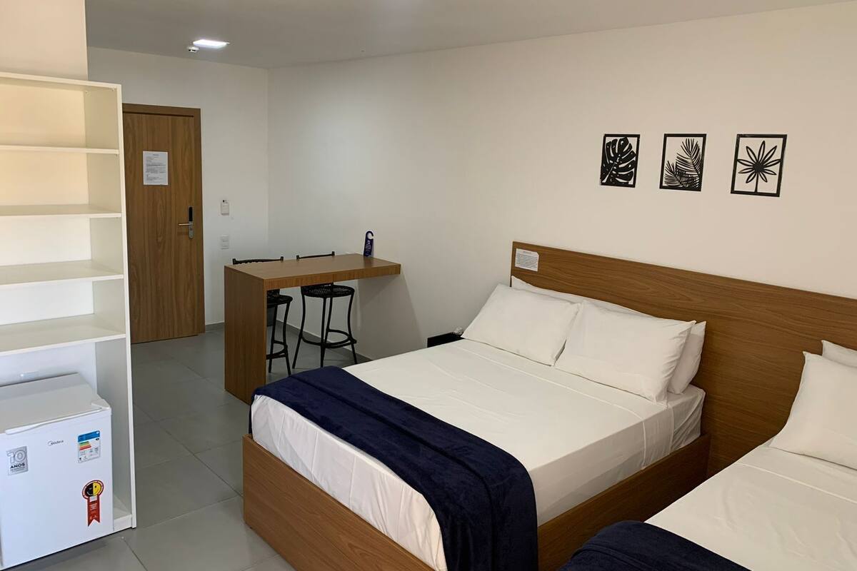Ein Hotelzimmer mit einem hölzernen Bett, einem Schreibtisch mit zwei Stühlen und einem weißen Kleiderschrank.