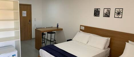 A hotel room with a wooden bed, a desk with two chairs, and a white wardrobe.