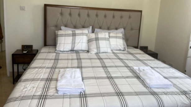A neatly made bed with a plaid bedspread and two folded towels. - Tranquil 2-bedroom apartment in Beautiful Barbados (Saint Philip)