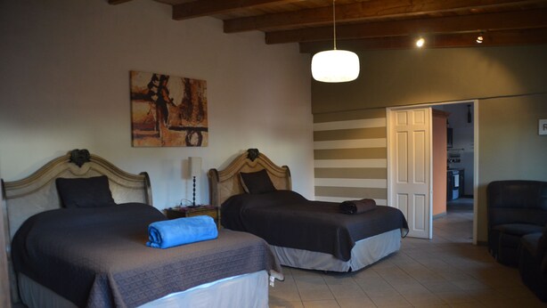 Ein Schlafzimmer mit zwei Betten, einem Bild an der Wand und einer Tür zu einem anderen Raum.
