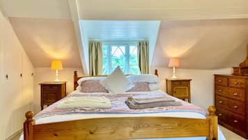 Une chambre à coucher avec un lit en bois, deux tables de chevet avec des lampes, une commode et une fenêtre avec des rideaux.
