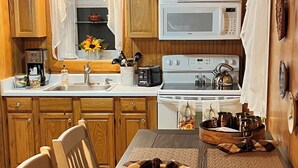 Una cocina de madera con una mesa de comedor dispuesta para cuatro personas, con un centro de mesa decorativo.