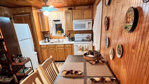 Una cocina con paneles de madera, una mesa de comedor, sillas y un microondas.