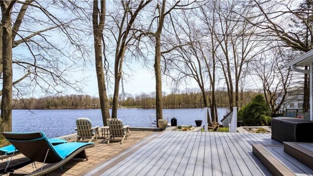 Terraza de madera con sillones de descanso y vistas a un lago.