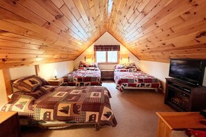 A cozy attic bedroom with two beds, a television, and a window with curtains. - Cozy Adirondack Mountain Cabin- Inlet, NY - Sleeps 9! (Inlet)
