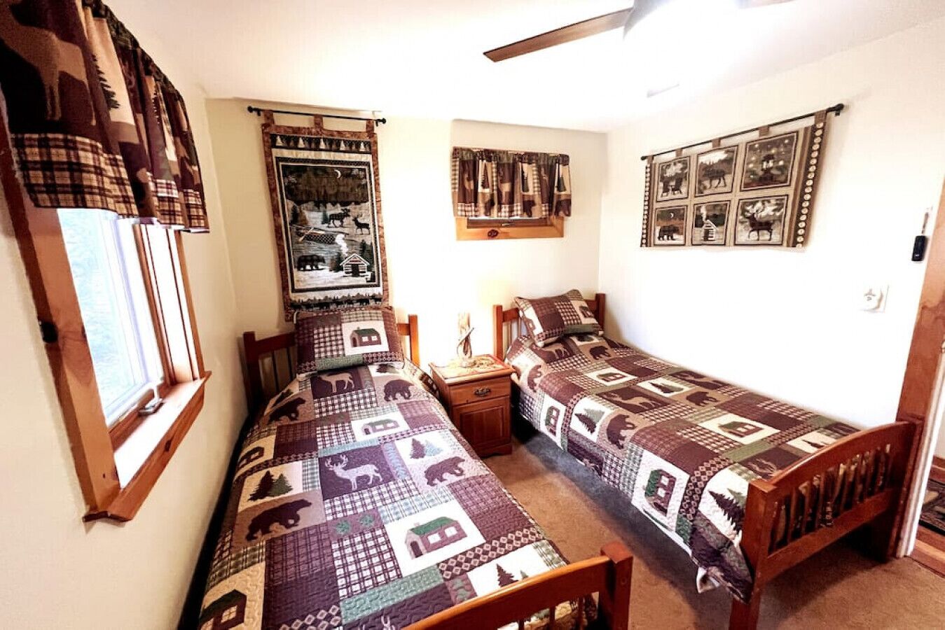 Een slaapkamer met twee eenpersoonsbedden, een nachtkastje, een raam met gordijnen en een muur met ingelijste foto's.