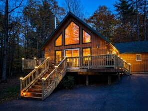 Una cabaña de madera con escalera, ventanas amplias y una terraza.