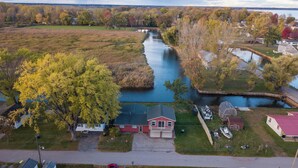 An aerial view of a riverside property with a house, a dock, and surrounding fields. - Catch on the Canal - Waterfront Getaway Near Casino, Dining & Entertainment (Standish)