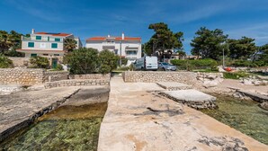 A stone pathway leading to a clear pool, surrounded by stone walls and greenery, with buildings in the background. - 1 bedroom stunning apartment in Kosljun (Kosljun)