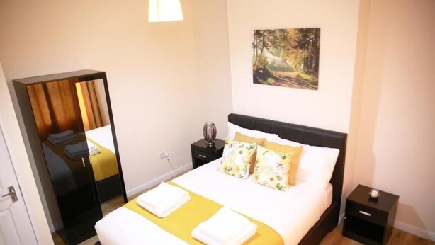 A neatly arranged bedroom with a bed, bedside tables, a mirror, and a painting on the wall. - Lovely 1-bedroom condo in Greater London (London)