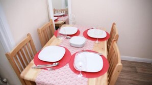 A dining table set for four with red placemats, white plates, and wine glasses. - Lovely 1-bedroom condo in Greater London (London)