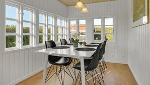 Spiseområde med et hvidt bord, sorte stole og store vinduer.