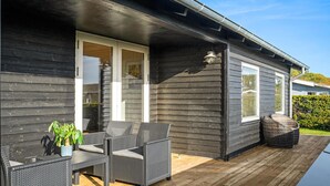 En træterrasse med fletningsmøbler og en potteplante.