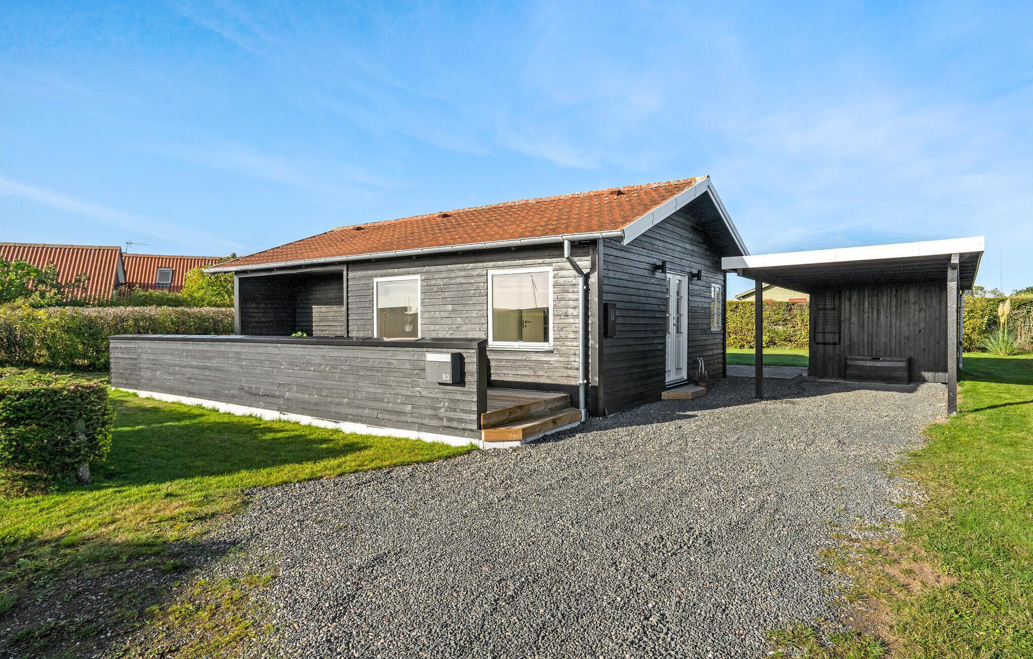 A modern two-story house with a gravel driveway and a well-maintained lawn.