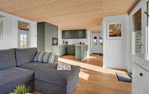 Ein modernes Wohnzimmer mit einem grauen Sofa, einem kleinen Couchtisch und einer Holzbalkendecke.