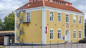 Een geel gebouw met een rood dak, een trap en een bordje dat aangeeft dat het een hotel is.