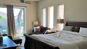 Une chambre avec un grand lit, deux ventilateurs de plafond, un bureau et une fenêtre avec des rideaux.