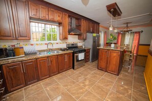 Enjoy cooking in this well-equipped kitchen with a central island, stainless steel sink, oven, and refrigerator.